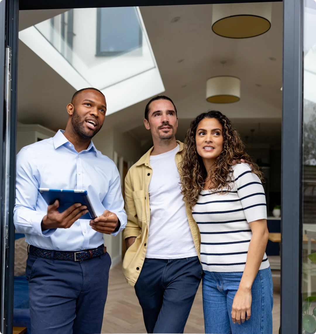 Homebuyers and agent in modern house doorway
